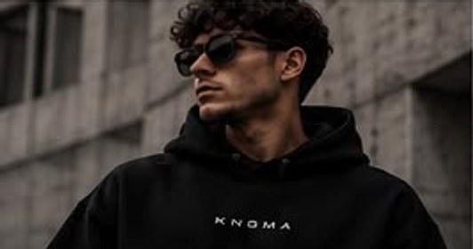 Model in een zwarte KNGMA-hoodie met borstprint
